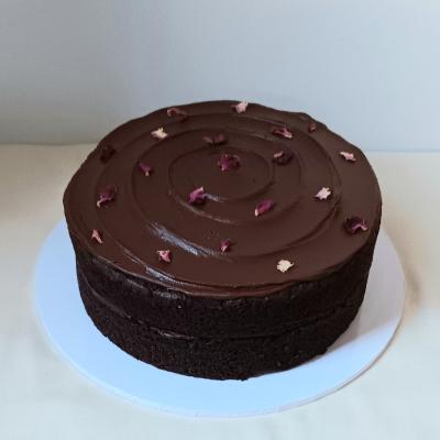 Sandwiched and topped with a rich, luxurious vegan fudgy chocolate ganache, decorated with edible dried rose petals.